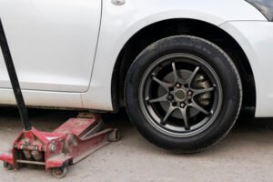 White cars change wheels using a lifting jack.